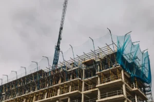 High-rise building under construction with crane and safety netting by San Diego Elite Scaffolding